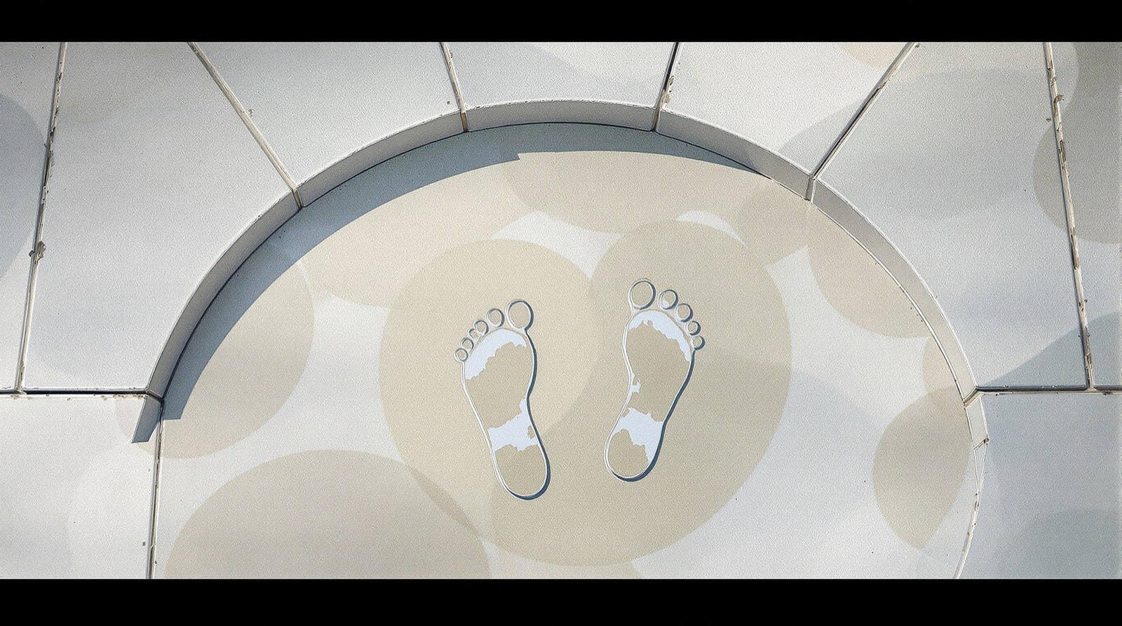 Wet footprints on a stone surface showing the shape of the arch